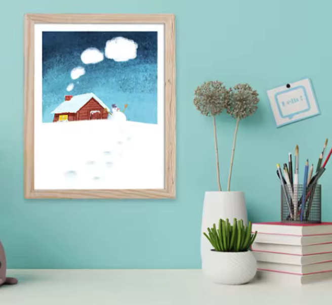 Gerahmtes Winterbild mit roter Hütte, Schneemann und Fußspuren an türkiser Wand über Schreibtisch mit Pflanzen.