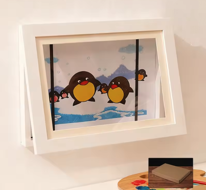Weißer Aufsteller-Rahmen mit cartoonhaften Pinguinen vor blau-weißer Winterkulisse, unten rechts kleine Verpackungsabbildung.